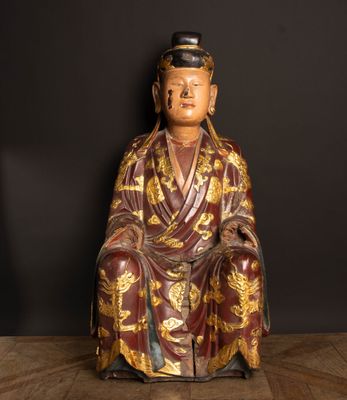 une vieille statue représentant un homme assis sur un plancher en bois