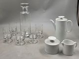 de nombreux verres, un pichet et des tasses sur la table