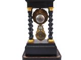 an antique black and gold clock sitting on top of a wooden stand