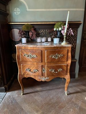 une commode en bois avec un plateau en marbre sur lequel est posée une bougie