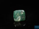 an image of a green and white stone sitting on top of a black surface