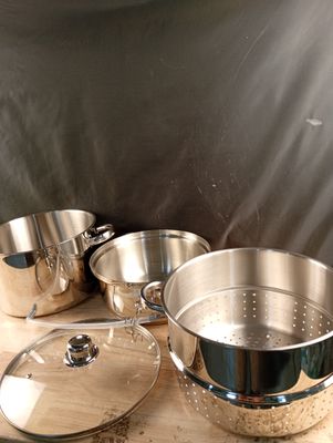 Plusieurs casseroles et poêles sont posées sur une planche à découper en bois.
