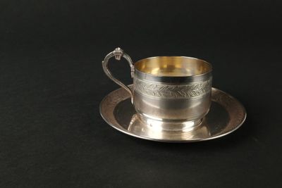 une tasse et une soucoupe argentées posées sur une table noire