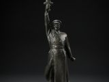 a bronze statue of a man holding a sword on a pedestal