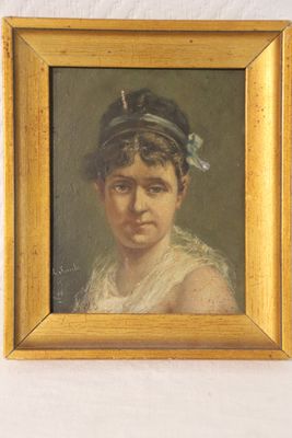 portrait of a young woman in a blue hat by a white wall
