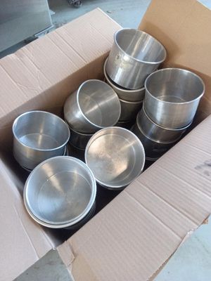 une boîte en carton remplie de casseroles en métal posée par terre