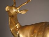 a golden deer statue on a pedestal against a gray wall
