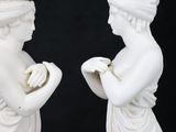 pair of white statues of a woman and a man holding hands