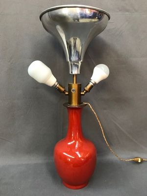 une image représentant un vase rouge surmonté d'une cloche en laiton