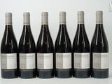six bottles of wine are lined up in a row on a white surface