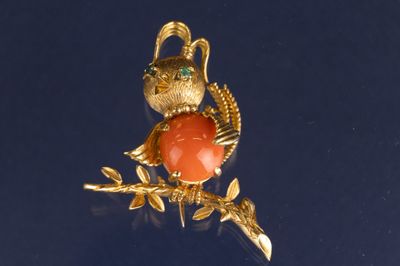 un oiseau doré orné d'une pierre rouge, perché sur une branche d'arbre
