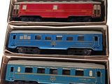 three blue and red train cars in boxes on a white surface