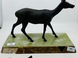 statue d'un cerf noir sur un socle vert, à côté d'un triangle