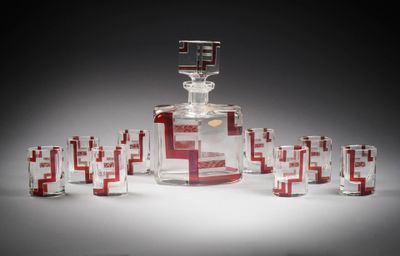 une carafe en verre, devant laquelle se trouvent plusieurs verres à shot