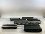 Plusieurs trains miniatures sont alignés sur une table devant un fond blanc.