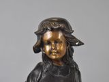 bronze statue of a young boy with a hat on his head