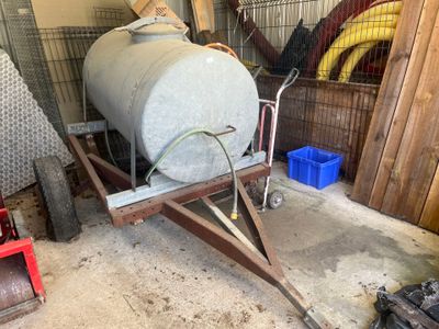 un grand réservoir posé sur un chariot dans un garage