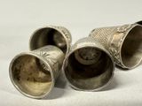 three silver cups that are sitting on a white surface
