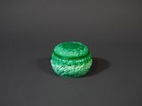 une boîte en verre vert posée sur une surface noire