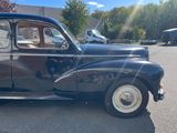 an old car parked in a parking lot with other cars in the background