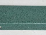 une vieille valise verte posée sur une table blanche