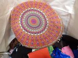 a colorful pillow sitting on top of a pile of clothes