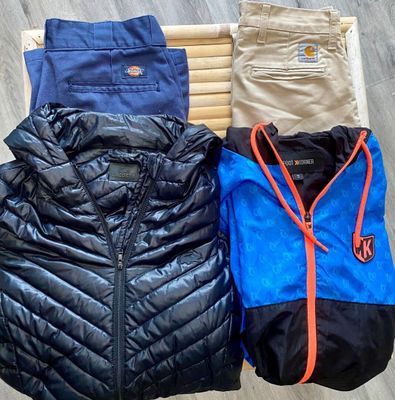 Plusieurs vestes et pantalons sont suspendus sur un portant en bois
