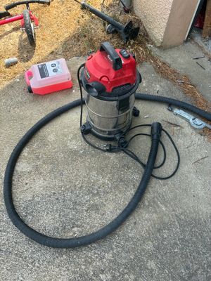 a red and black vacuum sitting on the concrete