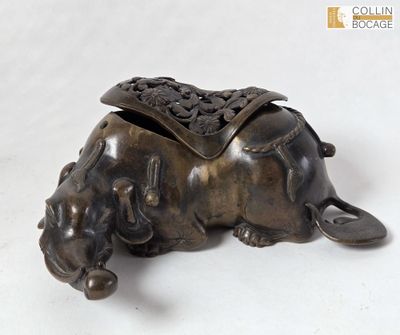 un petit éléphant en bronze avec une selle sur le dos