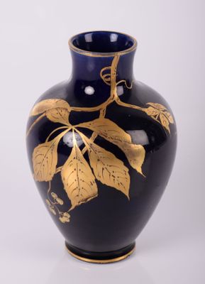 un vase bleu orné de feuilles dorées sur fond blanc