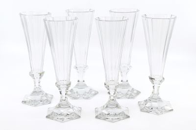 four clear glass wine glasses sitting next to each other on a white surface