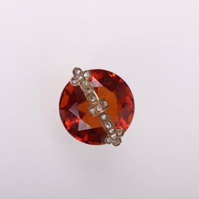 un gros plan sur une broche en pierre rouge et diamants