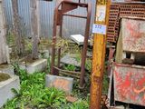 une grue rouillée posée dans l'herbe à côté d'un tas de ferraille