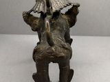 statue en bronze représentant un homme assis sur une chaise, avec un oiseau sur la tête