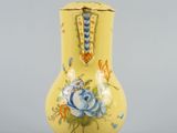 a yellow vase with blue and yellow flowers on it