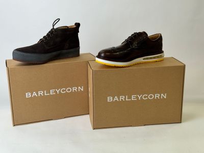 deux paires de chaussures sont posées sur des cartons, sur une surface blanche