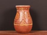 un vase marron posé sur une table, avec un mur noir en arrière-plan