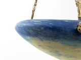 a blue and yellow bowl hanging from a gold chain