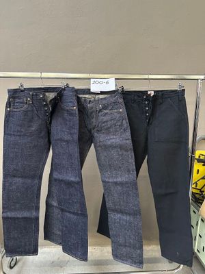 trois paires de jeans bleus suspendues à un portant dans un magasin