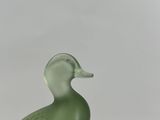 a green glass duck sitting on top of a wooden table