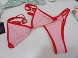a pink bikini with red trims on a white table