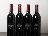 four bottles of wine are lined up on a wooden table