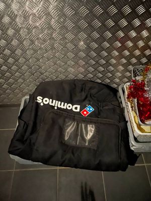 un sac de pizza posé par terre à côté d'une boîte à pizza