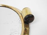 a mirror with a wooden handle on the wall
