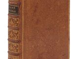 un vieux livre à la couverture brune posé sur une surface blanche