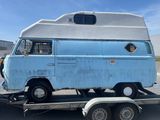 un vieux camping-car bleu sur une remorque, dans un parking