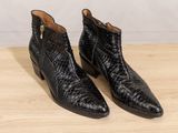 a pair of black leather ankle boots on a wooden table