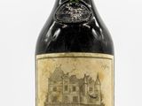 an old bottle of wine sitting on top of a white table