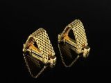 two pairs of gold earrings on a black surface
