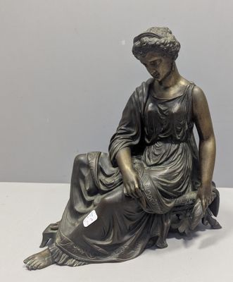 bronze statue of a woman sitting on a rock with a bird in her hand